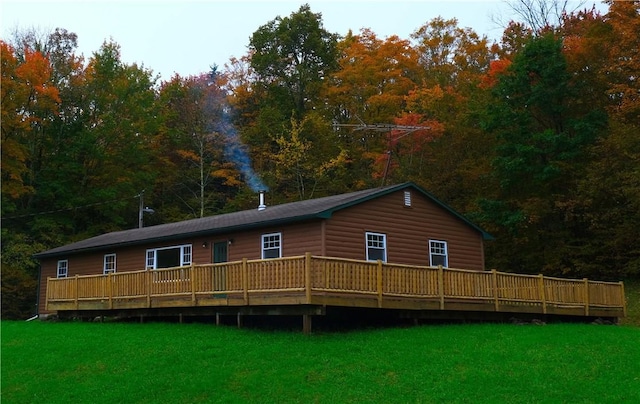 view of front facade with a front lawn, a wooden deck, and faux log siding