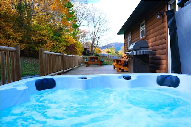 view of swimming pool with a deck with mountain view, grilling area, and a hot tub