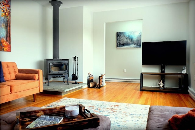 living room featuring a wood stove, wood finished floors, a baseboard heating unit, and baseboards