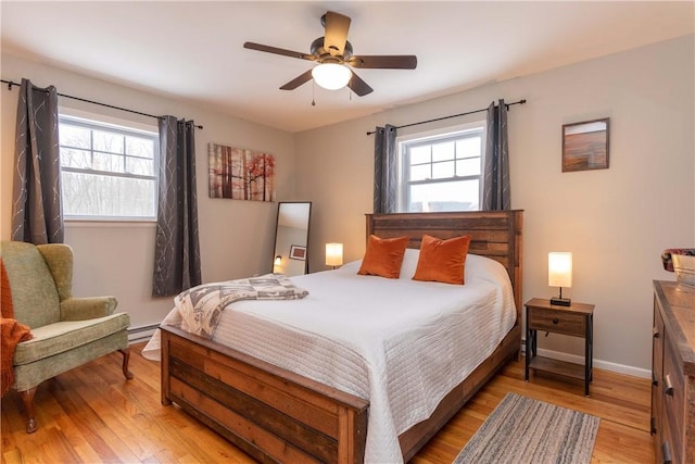 bedroom with multiple windows, light wood-style flooring, baseboards, and a ceiling fan