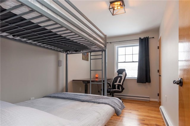 bedroom featuring light wood-style floors, a baseboard heating unit, baseboard heating, and baseboards
