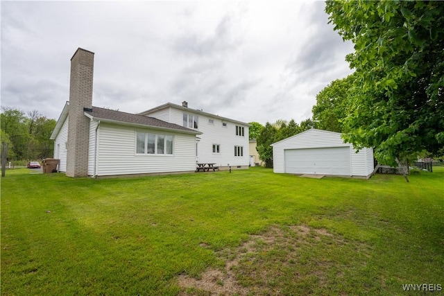 back of house featuring an outbuilding, a yard, a detached garage, and a chimney