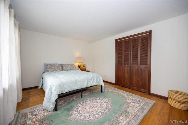 bedroom featuring light wood-style flooring, a closet, and baseboards
