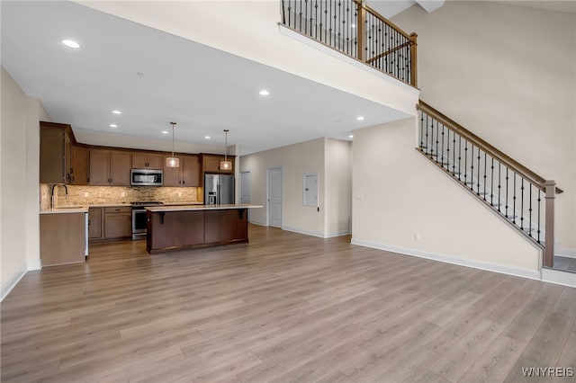 kitchen with stainless steel appliances, open floor plan, a sink, light countertops, and light wood finished floors