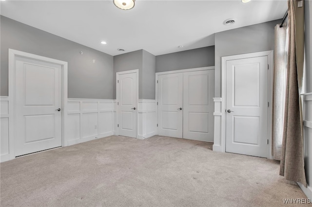 unfurnished bedroom with carpet flooring, wainscoting, a closet, and recessed lighting