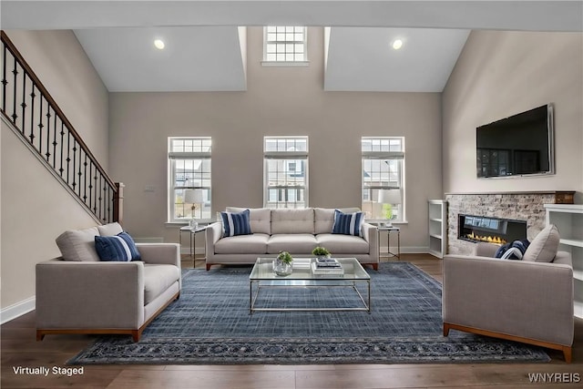 living room featuring healthy amount of natural light, baseboards, and a high ceiling
