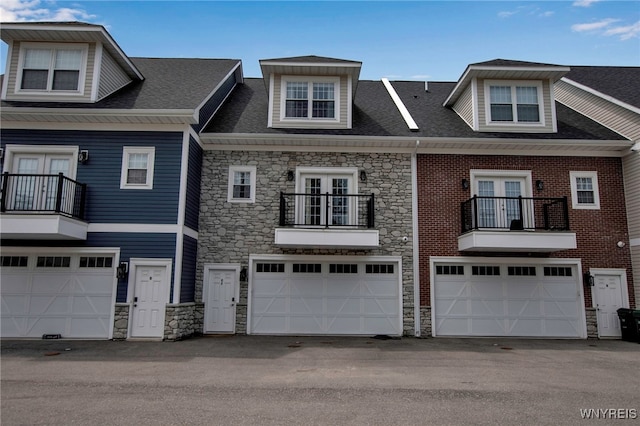 view of property with stone siding, french doors, and a balcony