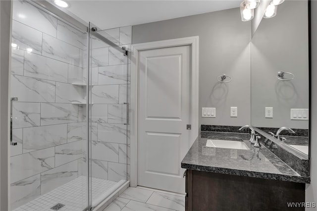 bathroom with marble finish flooring, a shower stall, and vanity