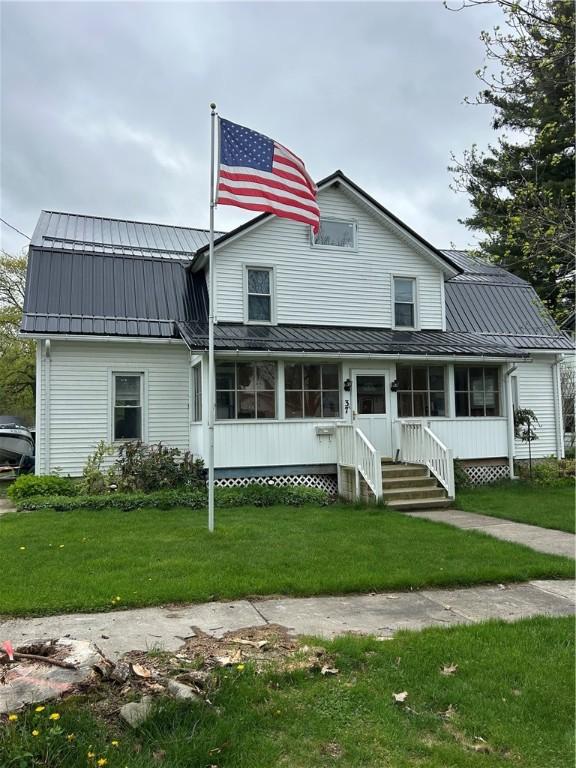 view of front of property with metal roof, a standing seam roof, a front yard, and a sunroom