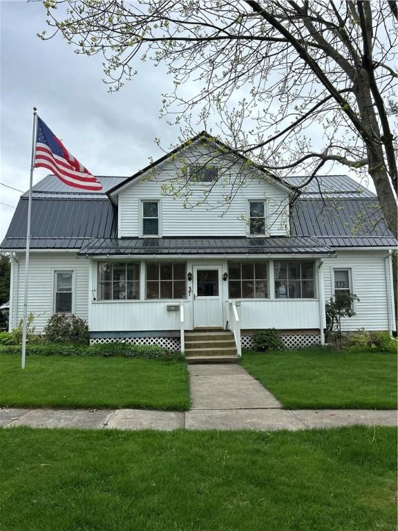 view of front facade with metal roof, a front yard, and a standing seam roof