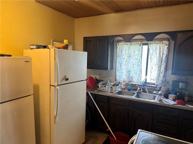 kitchen featuring freestanding refrigerator, a sink, wooden ceiling, and tile patterned floors