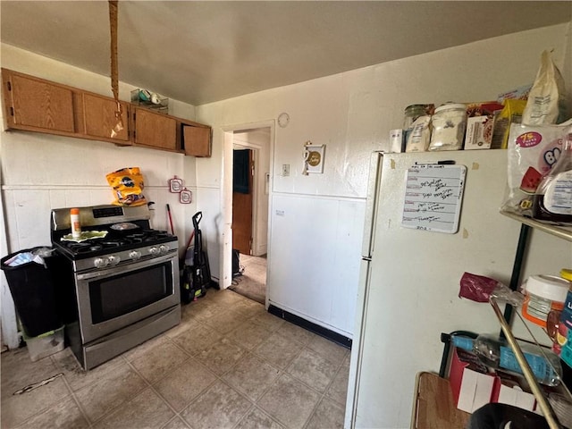 kitchen with gas range, brown cabinetry, and freestanding refrigerator