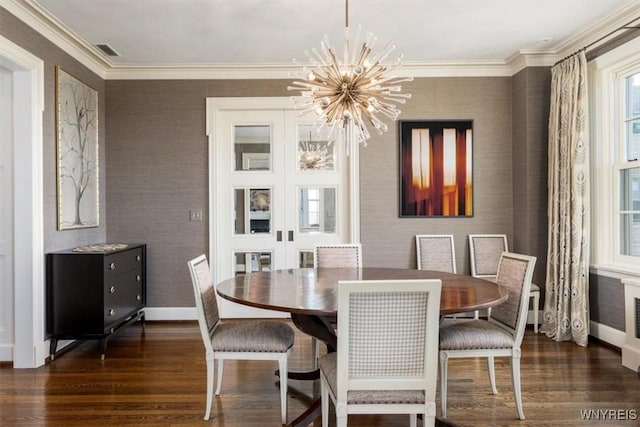 dining room with wood finished floors, a chandelier, baseboards, wallpapered walls, and ornamental molding