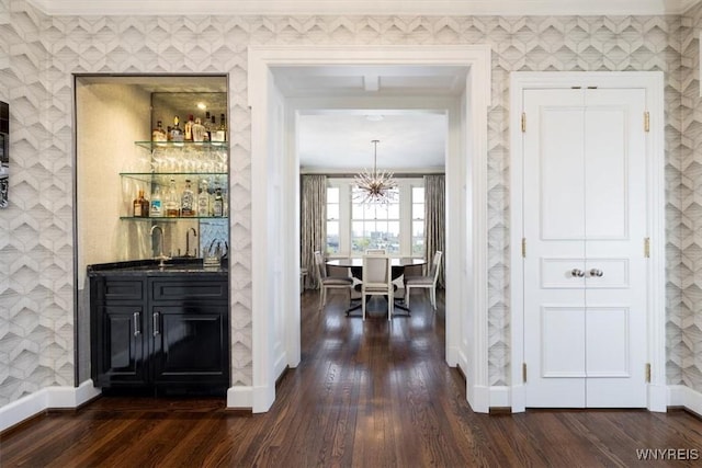 indoor wet bar featuring dark wood-style floors, baseboards, and a chandelier