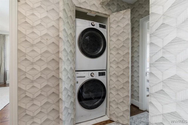 clothes washing area with stacked washing machine and dryer and tile walls