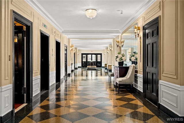 lobby featuring a decorative wall, ornamental molding, and a wainscoted wall
