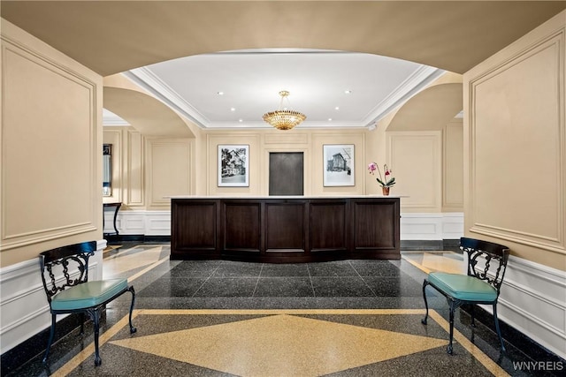 welcome area featuring a decorative wall, arched walkways, crown molding, recessed lighting, and a wainscoted wall