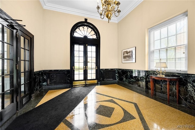 entryway with french doors, inlaid floor details, crown molding, a chandelier, and wainscoting
