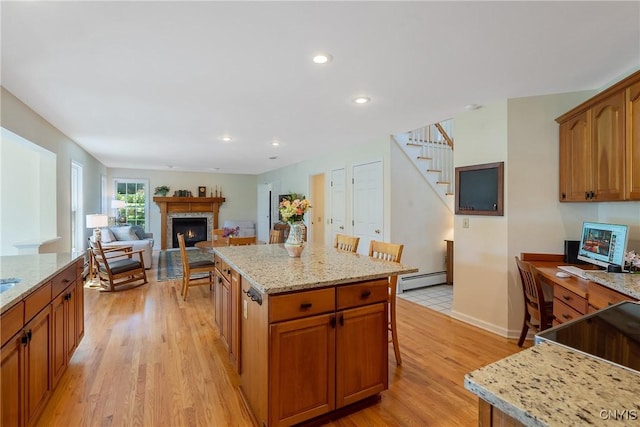 4268 Colorado Run, Onondaga, NY 13215 - kitchen with a kitchen breakfast bar, light wood-style floors, a warm lit fireplace, a center island, and light stone countertops