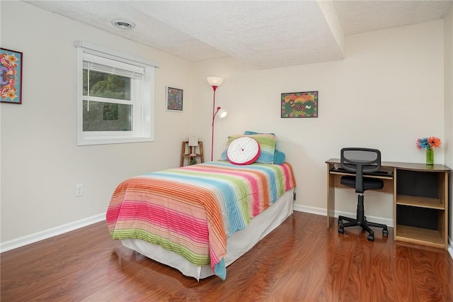 bedroom featuring a textured ceiling, wood finished floors, and baseboards