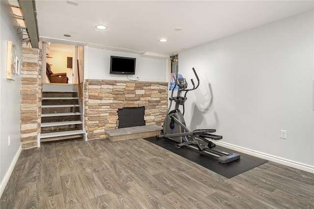 workout area with wood finished floors, baseboards, recessed lighting, and a fireplace