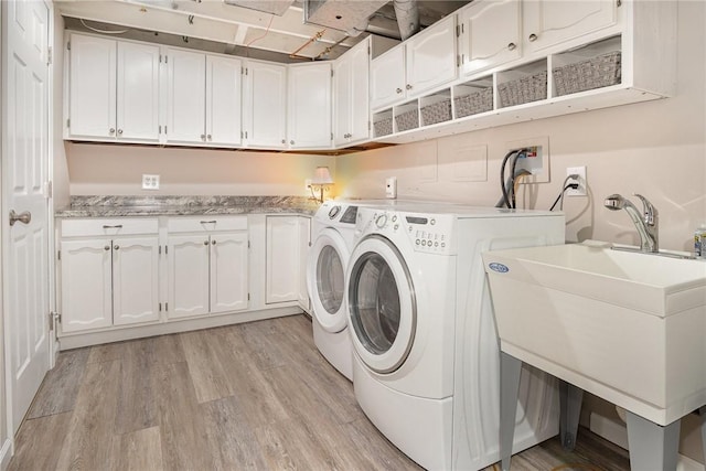 washroom with cabinet space, light wood finished floors, and separate washer and dryer