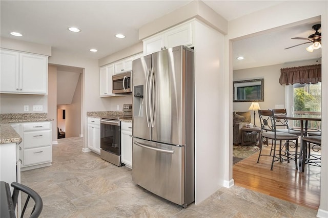 kitchen featuring appliances with stainless steel finishes, white cabinetry, light stone countertops, ceiling fan, and recessed lighting