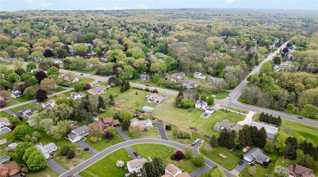 aerial view of property and surrounding area with a forest and nearby suburban area