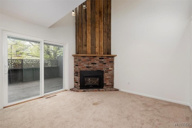 unfurnished living room featuring carpet flooring, a brick fireplace, baseboards, and vaulted ceiling