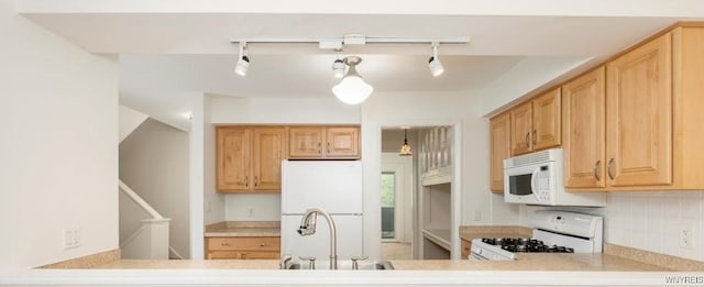kitchen featuring white appliances, rail lighting, a sink, light countertops, and light brown cabinetry