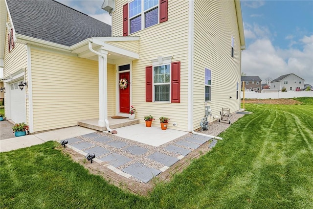view of front of home with a front yard, roof with shingles, and a garage