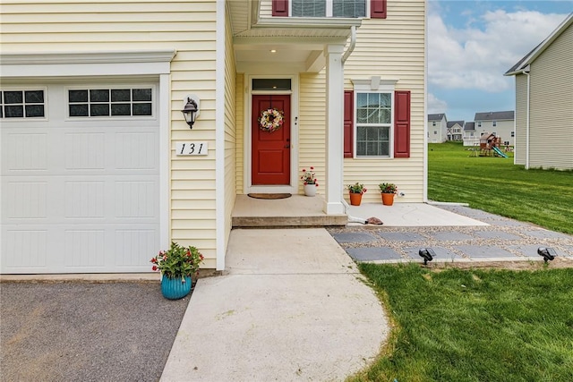 view of exterior entry with a garage and a yard