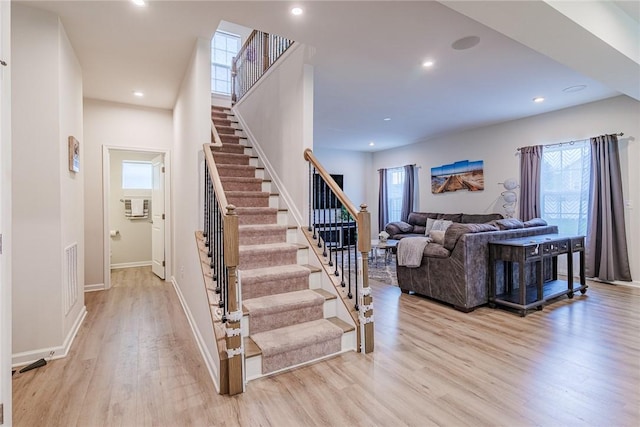 staircase featuring wood finished floors, plenty of natural light, recessed lighting, and baseboards