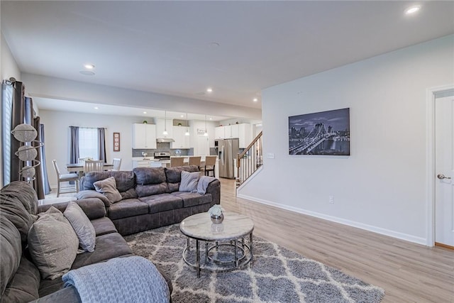 living area with light wood finished floors, recessed lighting, baseboards, and stairway