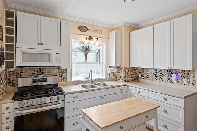 kitchen featuring white microwave, gas stove, a sink, decorative backsplash, and ornamental molding