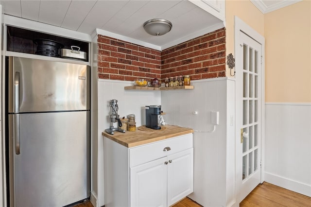 kitchen with freestanding refrigerator, wooden counters, wainscoting, white cabinetry, and light wood-style floors
