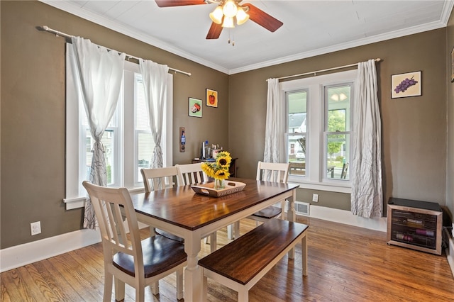 dining room with a ceiling fan, wood finished floors, ornamental molding, and baseboards