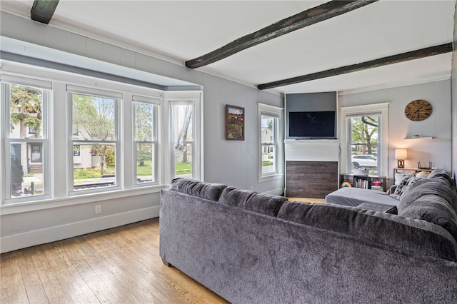 living room featuring beam ceiling, light wood finished floors, and baseboards