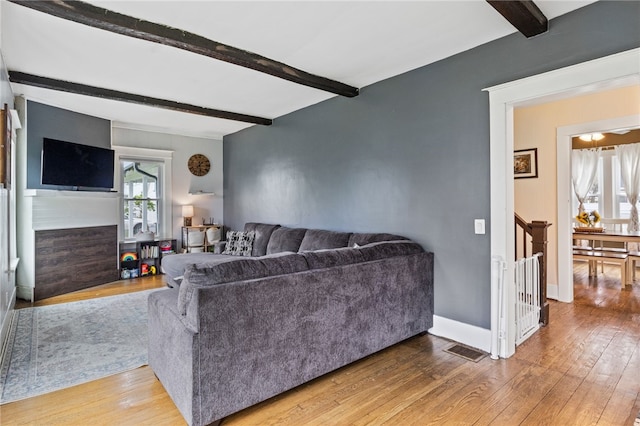 living area with beamed ceiling, hardwood / wood-style floors, stairway, and baseboards