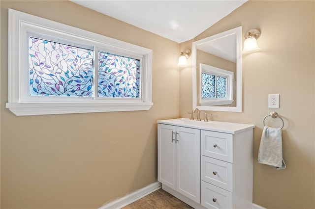 bathroom featuring baseboards, vanity, and vaulted ceiling