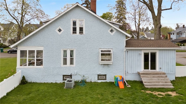 rear view of house with entry steps, a chimney, central air condition unit, and a shingled roof