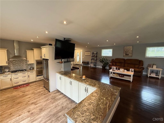 1404 Riverbend Dr, Lysander, NY 13027 - kitchen with a peninsula, wall chimney range hood, stainless steel appliances, open floor plan, and light wood-style flooring