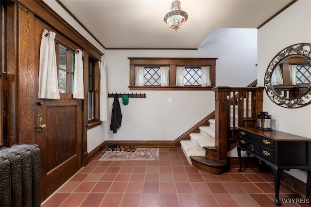 foyer featuring stairs, plenty of natural light, dark tile patterned flooring, and baseboards