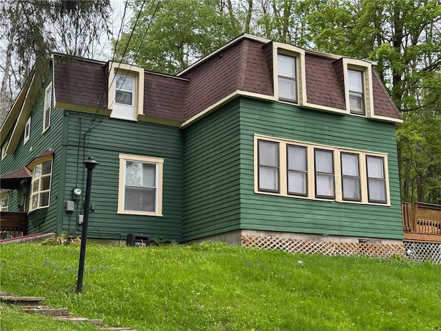 back of property featuring mansard roof, roof with shingles, and a lawn