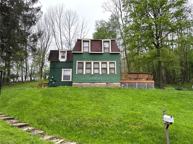 view of front facade with a deck, roof with shingles, mansard roof, and a front yard