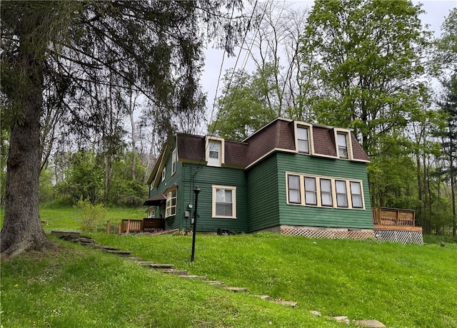 view of home's exterior with a deck, a lawn, mansard roof, and roof with shingles
