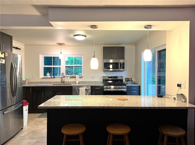 kitchen with stainless steel appliances, a sink, a kitchen bar, and light stone counters