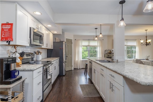 kitchen with appliances with stainless steel finishes, a sink, plenty of natural light, white cabinetry, and recessed lighting