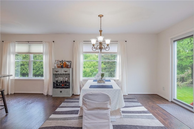 dining room with healthy amount of natural light, a chandelier, dark wood-type flooring, and baseboards