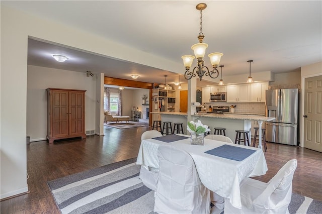 dining space with a chandelier, dark wood-style flooring, and baseboards
